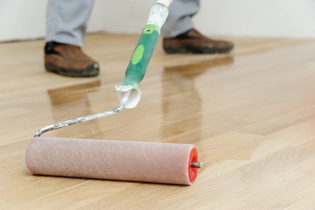 Image of person applying polyurethane on hardwood flooring.